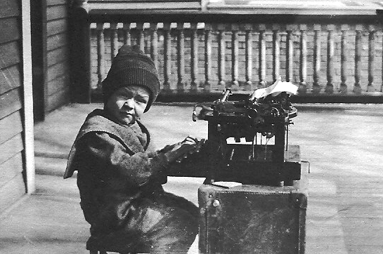 A vintage image of a young boy typing.